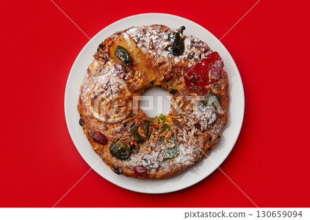 A close up of a festive cake on a white plate, surrounded by a checkered napkin and cutlery 130659094
