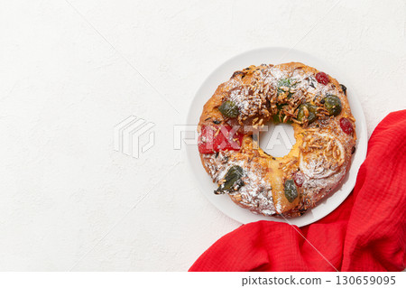 A festive wreath shaped cake with candied fruit and nuts, partially covered by a red napkin 130659095