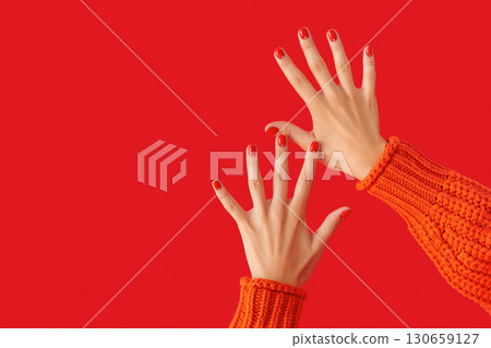 Womans hands with red manicure in orange sweater. Beauty salon concept Womans hands with red manicure in orange sweater. Beauty salon concept 130659127