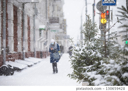 Snowfall on city streets. Blurred figure of a woman. that walks down the snowy street. 130659428