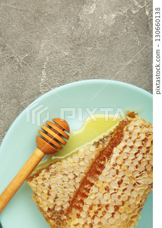 Sweet honey, dippers and combs on mint plate on grey concrete background. Vertical photo 130660138