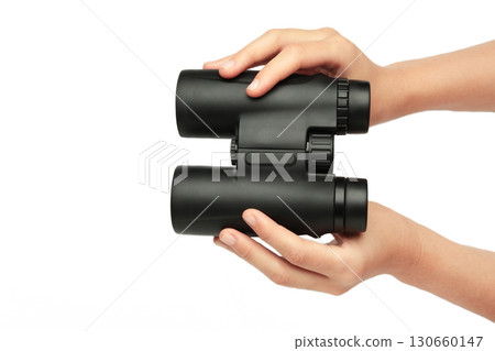 Female hand holds black binoculars isolated on white background. Looking through binoculars, journey, find and search concept 130660147