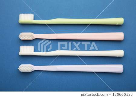 Pastel toothbrushes on dark blue background. Dental health and hygiene concept Pastel toothbrushes on dark blue background. Dental health and hygiene concept 130660153