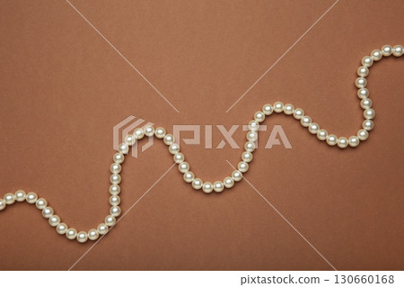 Elegant pearl necklace on brown background, top view. Elegant pearl necklace on brown background, top view. 130660168
