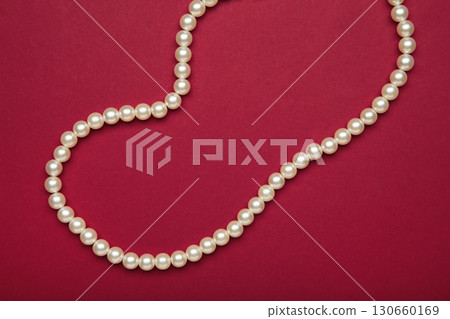 Elegant pearl necklace on red background, top view. 130660169