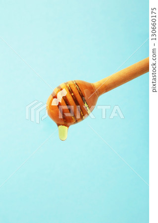 Wooden honey dipper with dripping honey on blue background 130660175