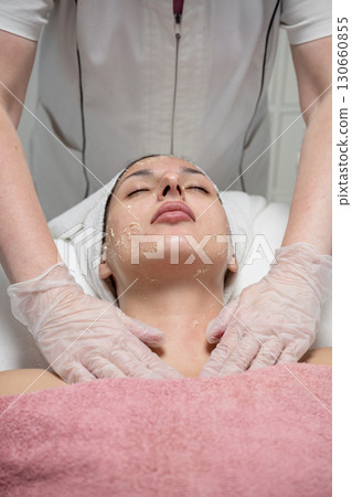 Beautician performing facial skincare treatment for female client in beauty salon 130660855