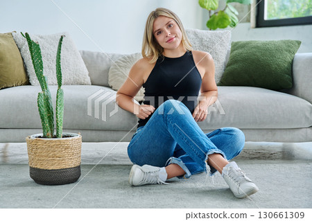 Portrait of relaxed beautiful young woman sitting at home on floor 130661309