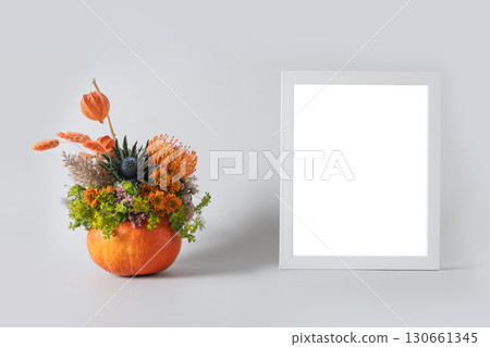 Autumn bouquet with orange and yellow flowers in pumpkin vase on blue background for Thanksgiving Day. Creative floral composition. Mock up. Space for design. Autumn bouquet with orange and yellow flowers in pumpkin vase on blue background for Thanksgiving Day. Creative floral composition. Mock up. Space for design. 130661345