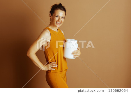 Smiling Woman with Protein Powder in Mustard Activewear 130662064