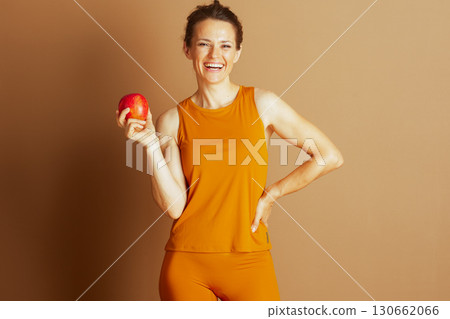 Joyful Woman in Orange Holds a Fresh Apple Joyful Woman in Orange Holds a Fresh Apple 130662066