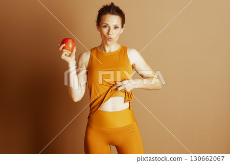 Yellow Activewear Woman Shows Midriff with Apple Yellow Activewear Woman Shows Midriff with Apple 130662067