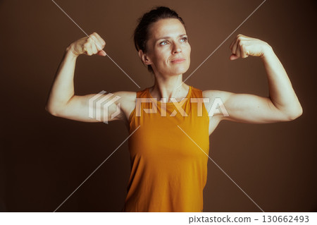 Determined Woman Flexing Bicep in Yellow Top 130662493
