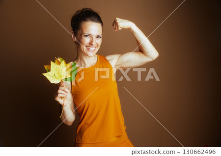 Strong Woman Flexing Bicep with Autumn Leaves Strong Woman Flexing Bicep with Autumn Leaves 130662496