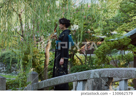 一位身著和服的女子在日式花園的橋上，柳樹下擺姿勢 | 日本傳統服飾與美麗 130662579
