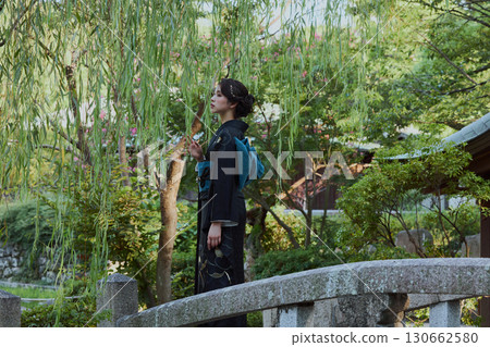 一位身著和服的女子在日式花園的橋上，柳樹下擺姿勢 | 日本傳統服飾與美麗 130662580