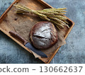 Bread background. Brown  whole grain loaf  on rustic dark wood  desk . Baking and home bread making concept. 130662637
