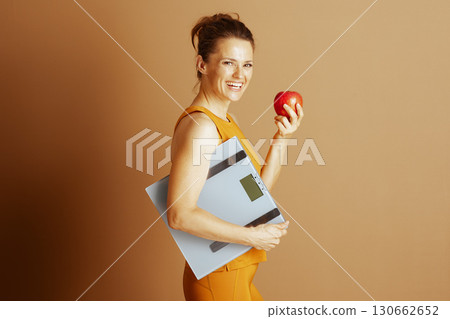 Woman Embracing Healthy Habits with Apple and Scale 130662652