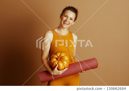 Smiling Fitness Woman with Yoga Mat and Fall Pumpkin 130662684