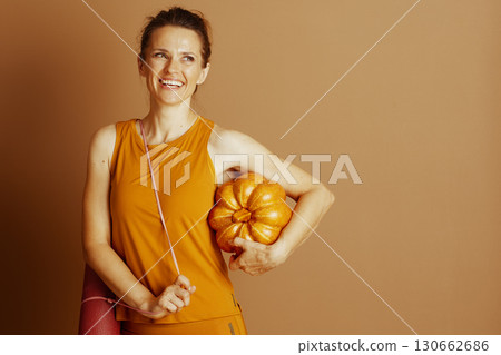 Seasonal Fitness: Woman with Yoga Mat and Pumpkin Seasonal Fitness: Woman with Yoga Mat and Pumpkin 130662686