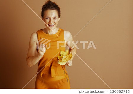 Joyful Fall Fitness: Woman with Autumn Leaves 130662715