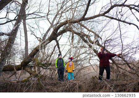 Exploring the winter landscape with children amidst twisted trees and a serene atmosphere near a tranquil creek at dusk Exploring the winter landscape with children amidst twisted trees and a serene atmosphere near a tranquil creek at dusk 130662935
