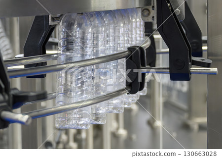 The  empty drinking water bottles  hanging on the overhead conveyor belt for filling process. 130663028