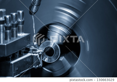 The lathe machine finish cut metal shaft parts with liquid coolant method in the blue tone scene. The lathe machine finish cut metal shaft parts with liquid coolant method in the blue tone scene. 130663029