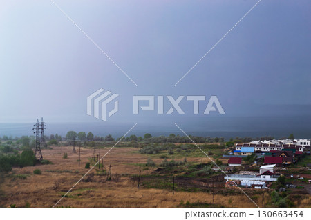 Heavy rain over the lake and a field with houses and power lines 130663454