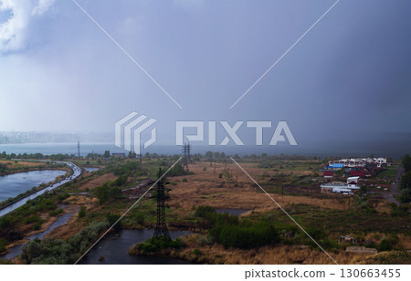 Heavy rain over the lake and a field with houses and power lines Heavy rain over the lake and a field with houses and power lines 130663455
