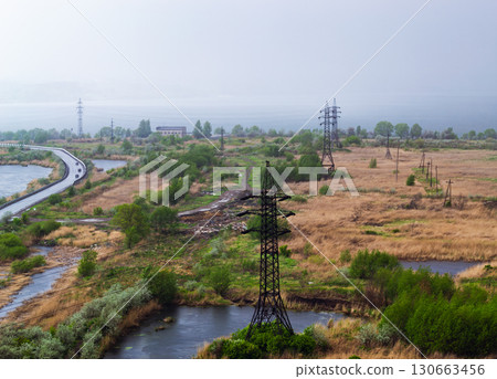 Heavy rain over the lake and the road behind the power line in the field Heavy rain over the lake and the road behind the power line in the field 130663456