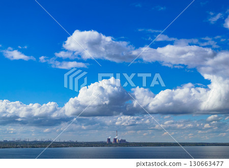 Industrial power plant by lake under blue sky 130663477