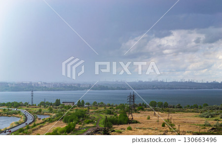 Rainstorm over lake and industrial cityscape 130663496