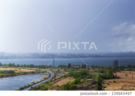 Rainstorm over lake and industrial cityscape 130663497