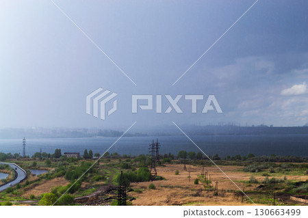 Rainstorm over lake and industrial cityscape 130663499