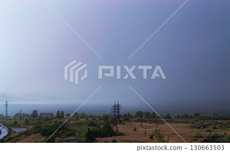 Rainstorm over lake and industrial cityscape 130663503