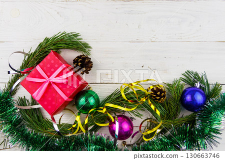 Christmas composition with fir tree branches, gift box and Christmas decorations on white wooden table. Top view, copy space 130663746