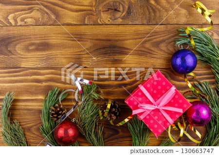 Christmas composition with fir tree branches, gift box and Christmas decorations on wooden table. Top view, copy space Christmas composition with fir tree branches, gift box and Christmas decorations on wooden table. Top view, copy space 130663747