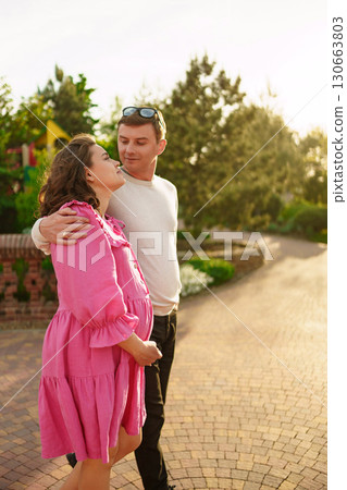 Man gently hugging pregnant woman while sitting in garden at home.  130663803