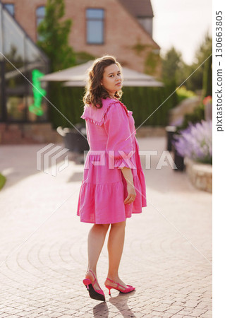 Beautiful pregnant young woman in pink dress on the path. view from the back 130663805