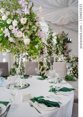 A composition of delicate flowers on the tables in the banquet hall. A composition of delicate flowers on the tables in the banquet hall. 130663835