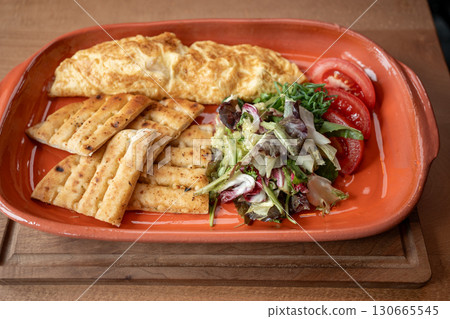 Delicious breakfast platter featuring fluffy omelette and fresh vegetables Delicious breakfast platter featuring fluffy omelette and fresh vegetables 130665545