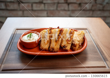 Delicious grilled cheese sandwiches with creamy dip on rustic wooden table 130665615