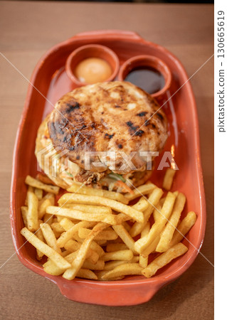 Savory burger and crispy fries served in a rustic style dish 130665619