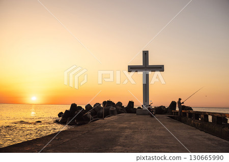 Fisherman standing near a large cross on the pier at sunset in Varna, Bulgaria Fisherman standing near a large cross on the pier at sunset in Varna, Bulgaria 130665990