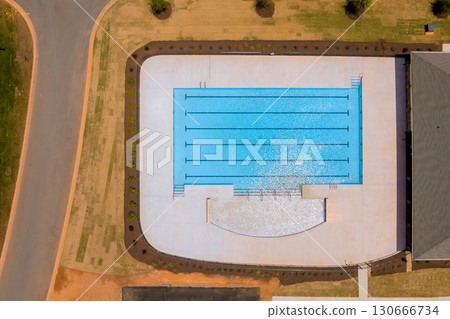 Aerial view of newly constructed swimming pool with lanes, surrounded by grass pavement in community area. 130666734