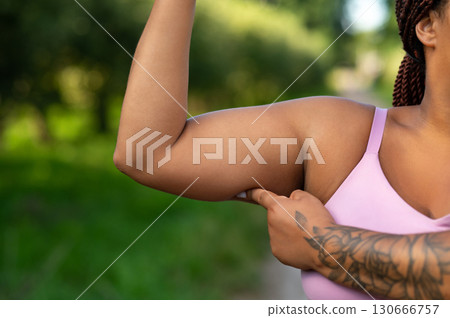 Closeup of African American woman flexing bicep in pink sportswear Closeup of African American woman flexing bicep in pink sportswear 130666757