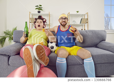 Funny family couple having cheat day, eating junk food and watching football on TV 130666766