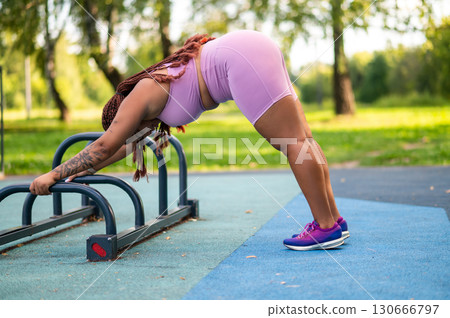 Plus size woman in activewear working out push ups at park Plus size woman in activewear working out push ups at park 130666797