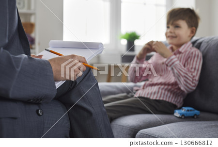 Woman psychologist or psychotherapist with pencil and clipboard talking to child 130666812